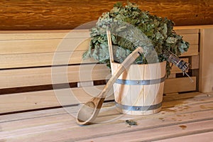 Wooden bucket and a birch broom in a bath on a wooden background