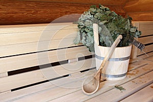 Wooden bucket and a birch broom in a bath on a wooden background