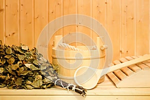 A wooden bucket, a birch broom and other accessories in a finnish classic sauna or russian bath. Free space on a wooden