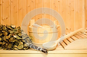 A wooden bucket, a birch broom and other accessories in a finnish classic sauna or russian bath. Free space on a wooden