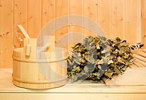 A wooden bucket, a birch broom and other accessories in a finnish classic sauna or russian bath. Free space on a wooden