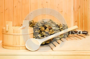 A wooden bucket, a birch broom and other accessories in a finnish classic sauna or russian bath. Free space on a wooden