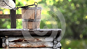 Wooden bucket on well rustic traditional fountain, source of pure water from nature