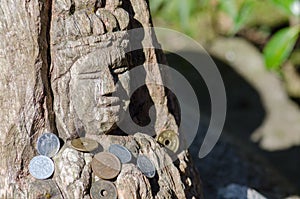 Wooden Buddha sculpture with donated coins at Kamakura