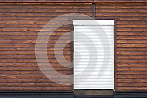 Wooden building facade. Brown wood siding wall with white shutter door. Copyspace