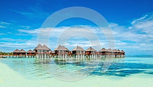 Wooden bungalow on the background of azure water and blue sky, Maldives