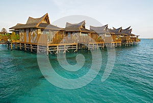 wooden bungalows over turquoise sea water