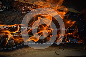 Wooden burning hot charred planks of wood logs in a fire with tongues of fire and smoke. Texture, background