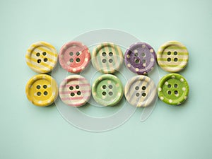 Wooden buttons with colored stripes and colorful dots on a pastel green background