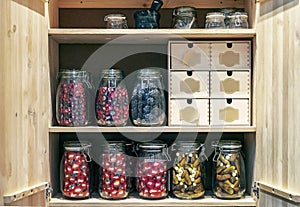 Wooden cabinet with glass jars of pickles and marinades in a conceptual style