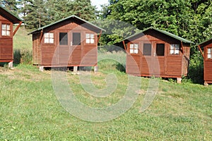 Wooden cabins or lodges as summerhouses in a forest with green grass on a sunny summer day