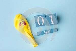 Wooden calendar with the date of April 1, on a blue background. April Fools' Day