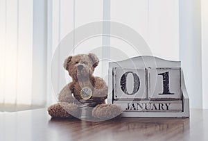 Wooden calendar first of January with teddy bear and stack pound coin, Concept for Financial planing for New Yew resolution for