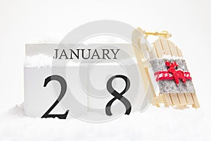 Wooden calendar for January, 28 th day of the winter month. The symbols of winter are snow and sleigh. Concept of holidays,