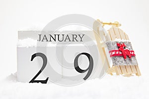 Wooden calendar for January, 29 th day of the winter month. The symbols of winter are snow and sleigh. Concept of holidays,
