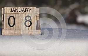 Wooden calendar of January 8 date standing in the snow in nature