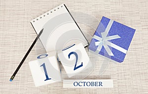 Wooden calendar for October 12, gift box in classic blue with a white ribbon, trend color numbers