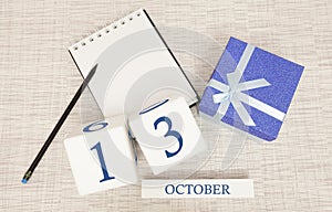 Wooden calendar for October 13, gift box in classic blue with a white ribbon, trend color numbers