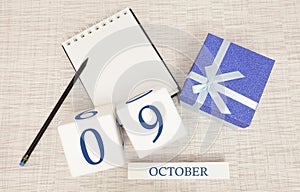 Wooden calendar for October 9, gift box in classic blue with a white ribbon, trend color numbers