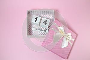 Wooden calendar in the pink gift box on the pink background.