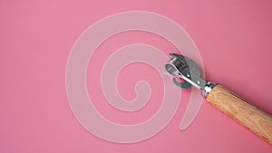 Wooden can opener on pink background
