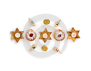 Wooden candlesticks in the shape of star, donuts, golden chocolate coins and wooden dreidels on white background