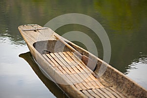 Wooden canoe with an oar on the calm lake water