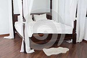 Wooden canopy bed and a white hide on the floor