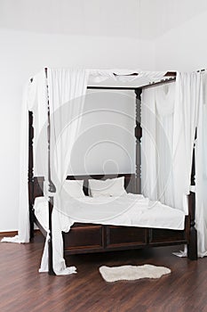 Wooden canopy bed and a white hide on the floor