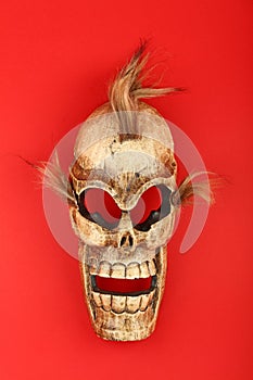 Wooden carved skull death mask on red