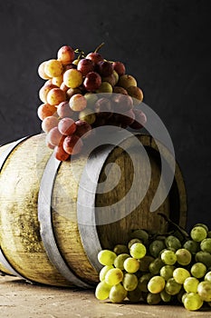 Wooden cask with wine and two grapes on a black background