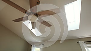 Wooden ceiling fan with lamp in modern interior with sunny windows. Wide shot