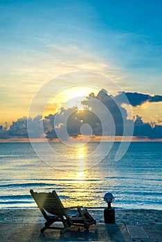 Wooden chair on beach and sea at sunset