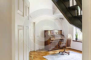 Wooden chair at classic piano in white interior of elegant house