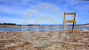 Wooden chair contemplating the shore of a reservoir