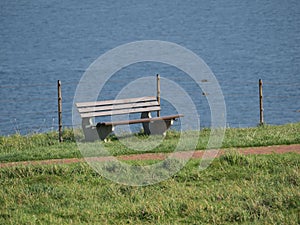 Wooden chair on the green grass by the water.