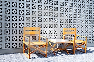 Wooden chairs with backrests are paired with small wooden tables in the rock garden for relaxing