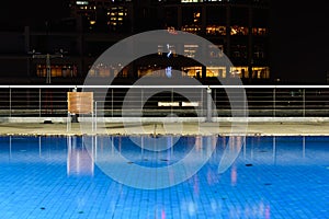 Wooden chairs are located at the hotel`s swimming pool at night