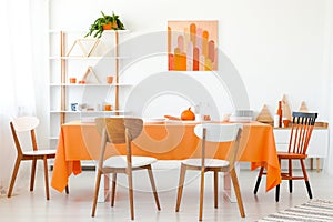 Wooden chairs at orange table in white dining room