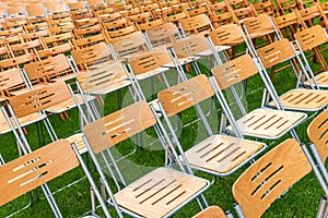 Wooden chairs outside in the park in the rain. Empty auditorium, grass and water drops