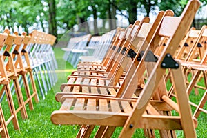 Wooden chairs outside in the park in the rain. Empty auditorium, grass and water drops