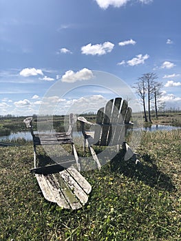 Wooden chairs on the shore of the marsh