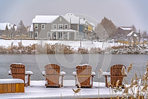 Wooden chairs on snowy lake deck in Daybreak Utah