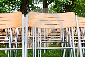 Wooden chairs stand outside in the park in the rain. Empty auditorium, green grass, waterdrops, closeup