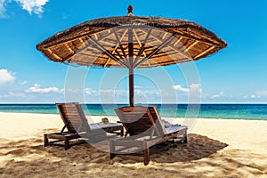 Wooden chairs and umbrellas on white sand beach