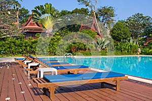 Wooden chaise lounges on the bank of pool.