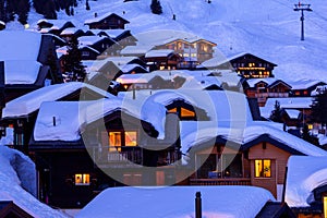 Wooden chalets covered with deep snow at blue hours