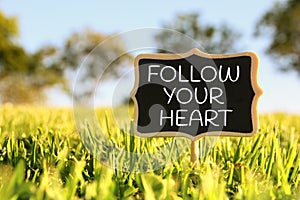 Wooden chalkboard sign with quote: FOLLOW YOUR HEART