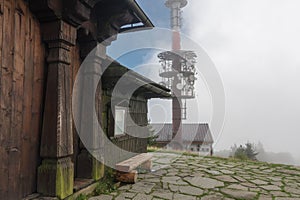 Wooden chapel , on background radio and televison transmitter on summer foggy day in Beskid mountains in Czech Republic