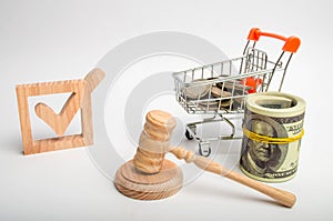 A wooden checkbox and a trolley with coins and a hammer of the judge. Lobbying of interests of investors and business groups, poli